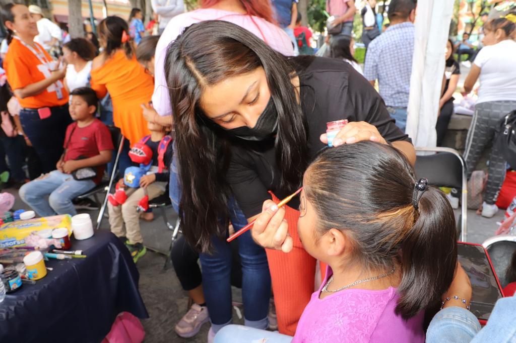 Pintan rostro a niños en el zócalo de Puebla.