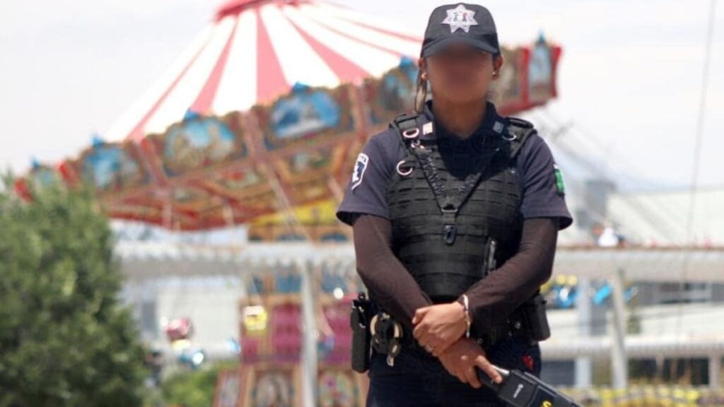Policía con detector de metal y al fondo juego de Feria de Puebla.
