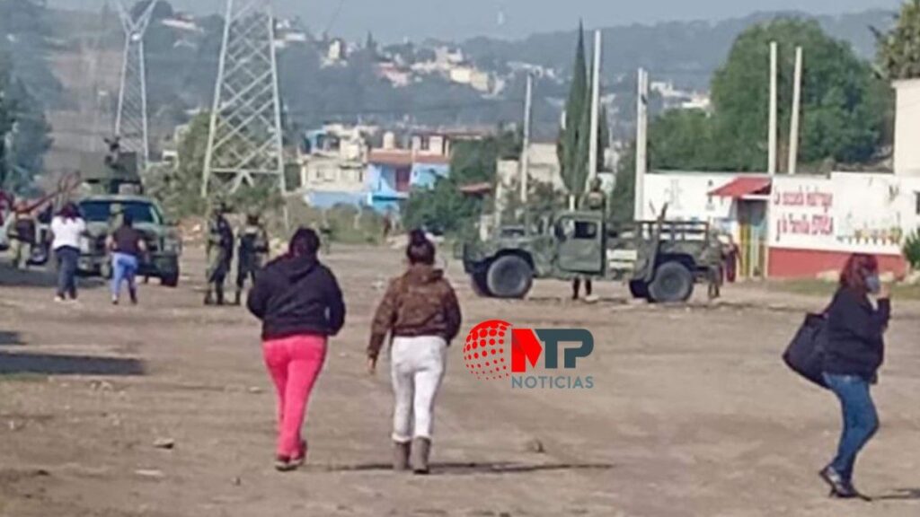 Militares revisan una casa en Amozoc mientras habitantes transitan por la zona.