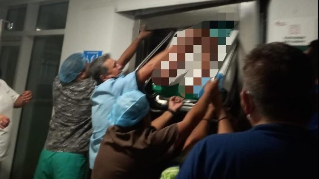 Personal médico y personas intentan sacar a niña aplastada por elevador.