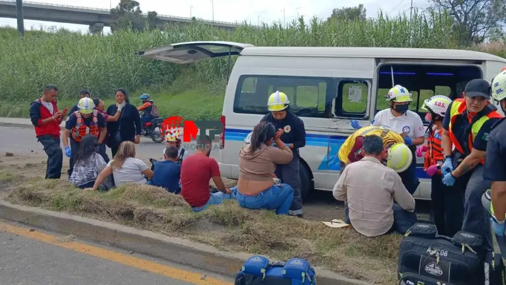 Personas sentadas en camellón luego de que su transporte chocara en la federal a Tlaxcala.