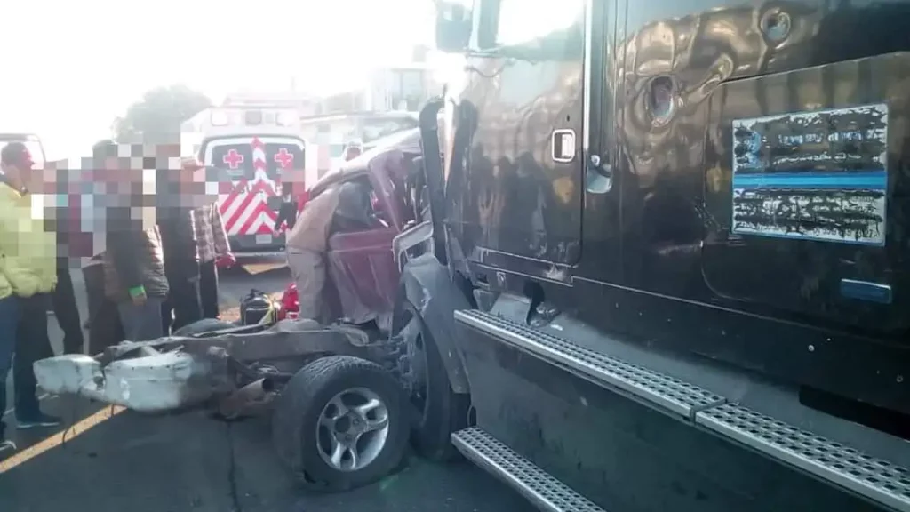 Camioneta destrozada por tráiler en la carretera federal México-Veracruz, una ambulancia estacionada al fondo.