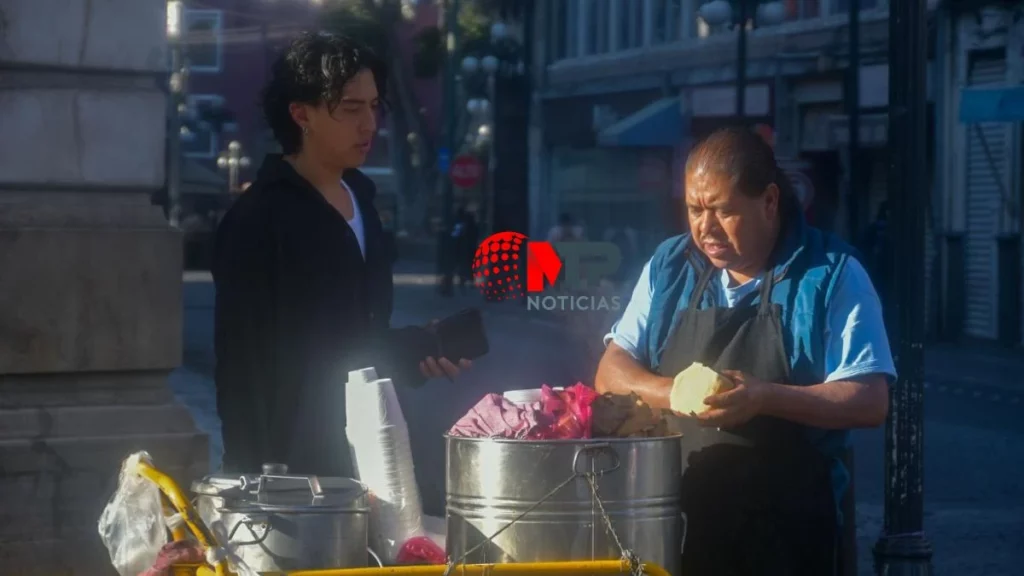 Señor tamalero vendiendo torta de tamal a joven en centro de Puebla.