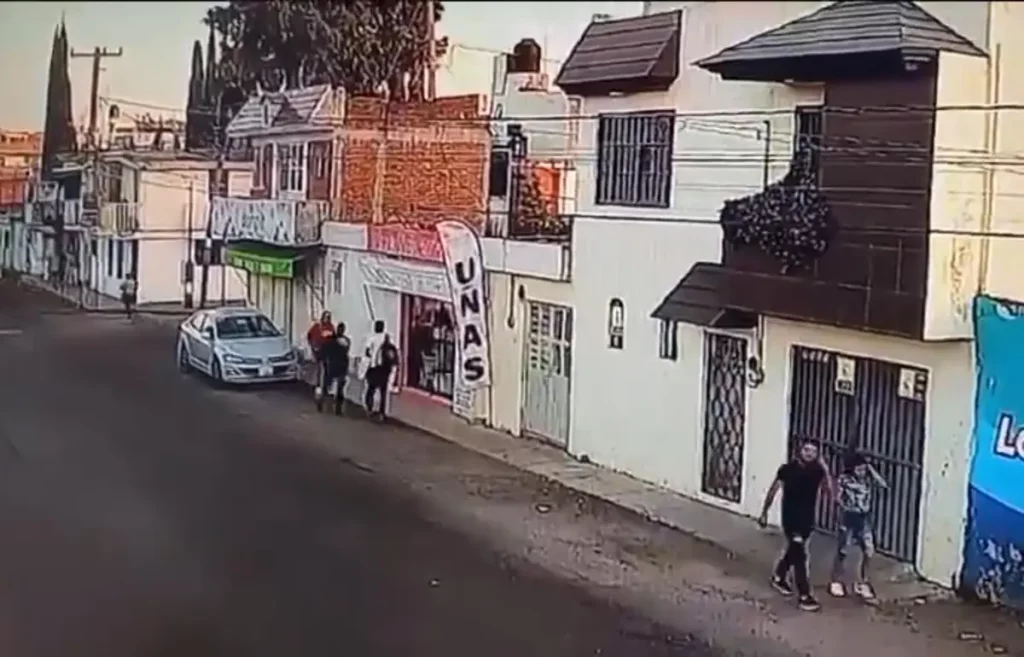 Dos hombres armados asaltan a personas que se encuentran cerca de auto estacionado en una calle.