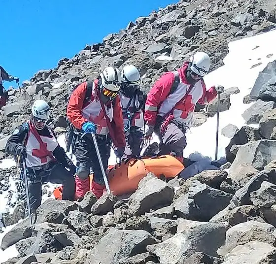 Paramédicos de Cruz Roja Puebla cargan cuerpo de alpinista fallecida en Pico de Orizaba tras extraviarse.