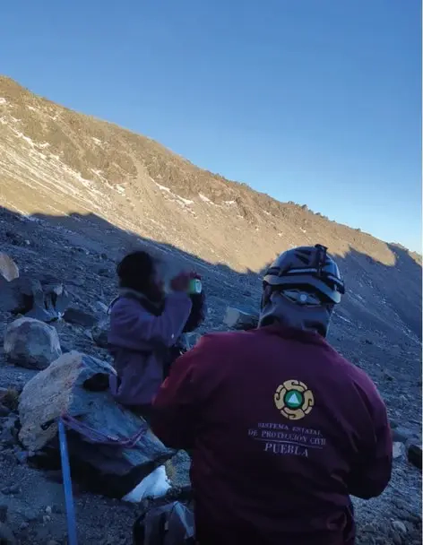 Trabajador de Protección Civil de Puebla atiende a alpinista deshidratado tras extraviarse en el Pico de Orizaba.