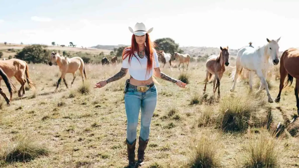 Activista Elena Larrea en pastizal rodeada de caballos.