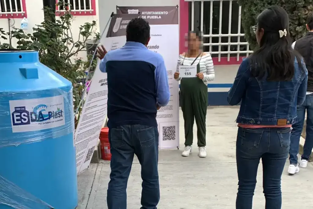 Personal del Ayuntamiento de Puebla toman foto a mujer que recibió tinaco azul.