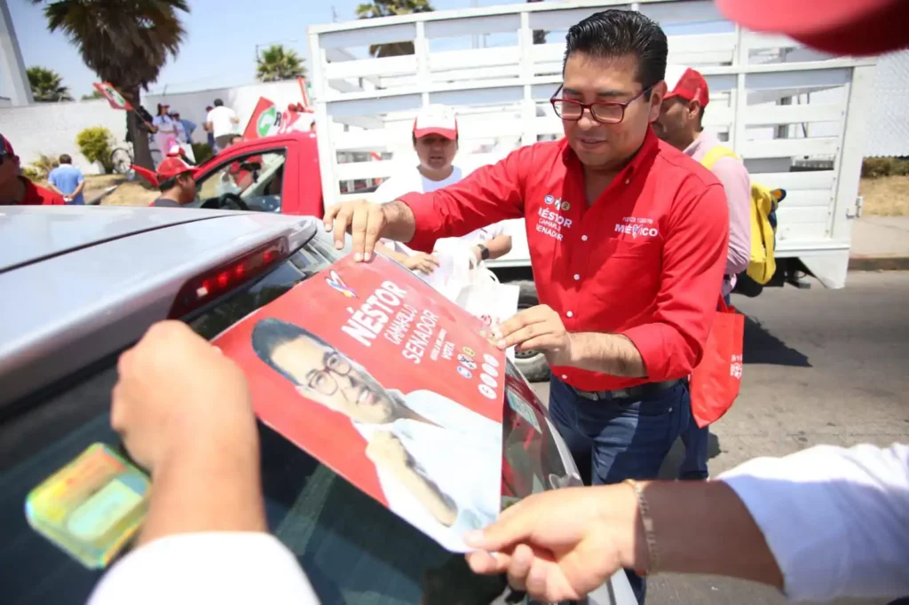 Néstor Camarillo pega calcomanía en auto en campaña electoral.