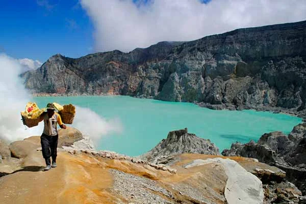 Cráter de volcán en Indonesia con lago y una persona parada en la orilla.