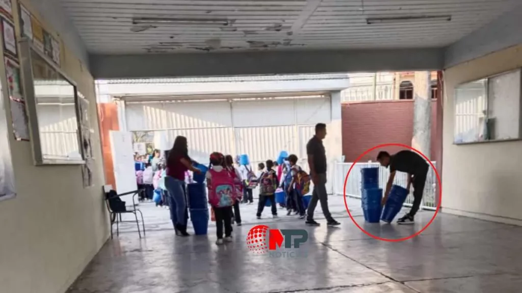 Personas entregan cubetas azules a niños a la salida de la escuela en Cuautlancingo.