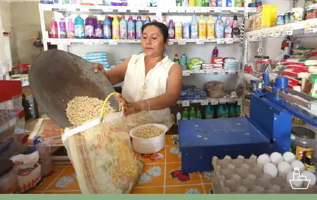 Mujer en tienda vaciando maíz en una bolsa.