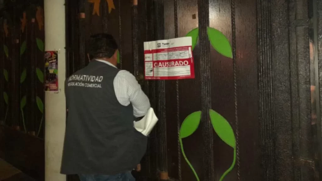 Persona de Protección Civil Municipal de Puebla colocando sello de clausura en puerta de bar.