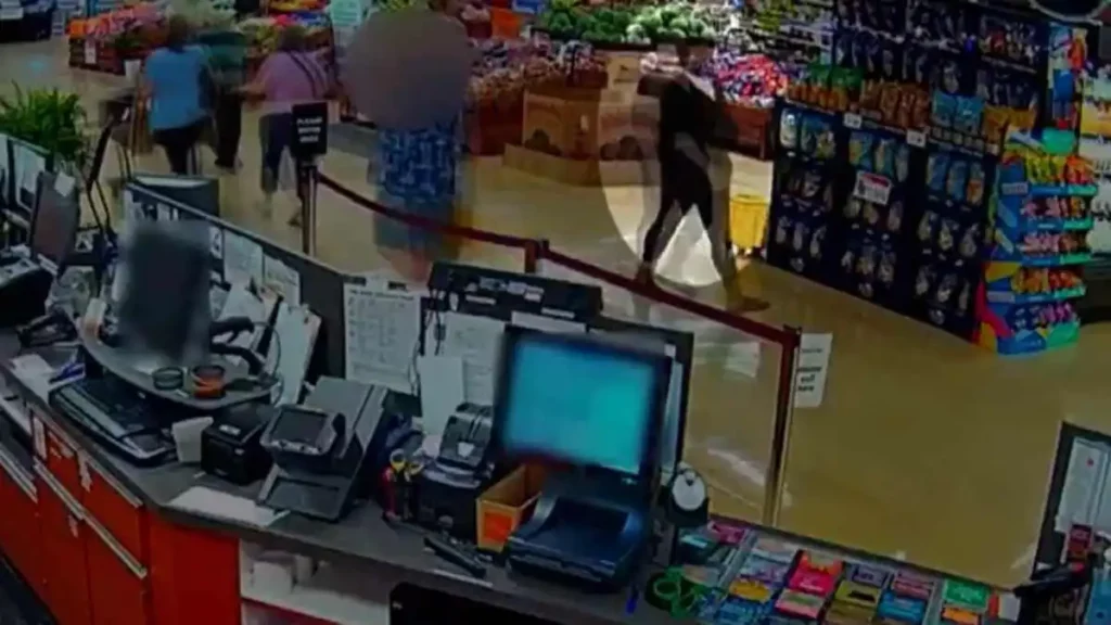 Mujer camina en pasillo en supermercado con un cuchillo en la mano.