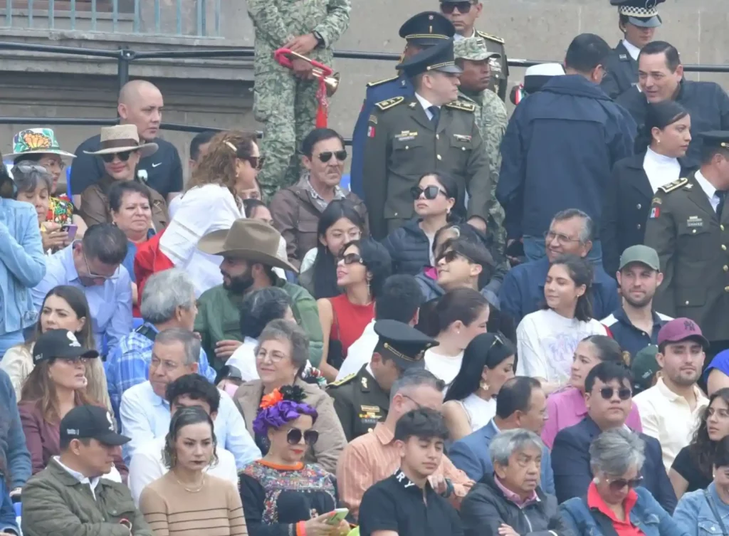 Ángela Aguilar y Christian Nodal en gradas observando desfile en CDMX.