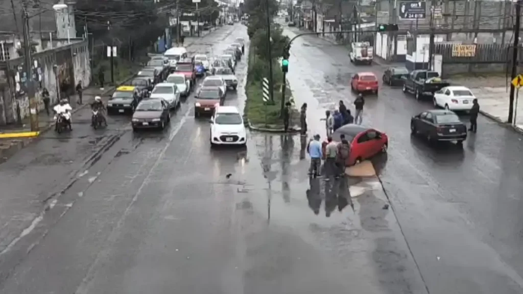 Hombres rodean auto luego de voltearlo tras volcadura en vialidad.