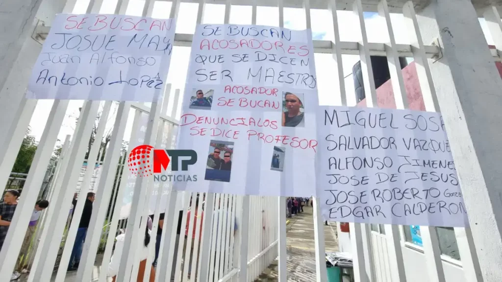 Cartulinas en reja de escuela tras protesta contra maestros acosadores.