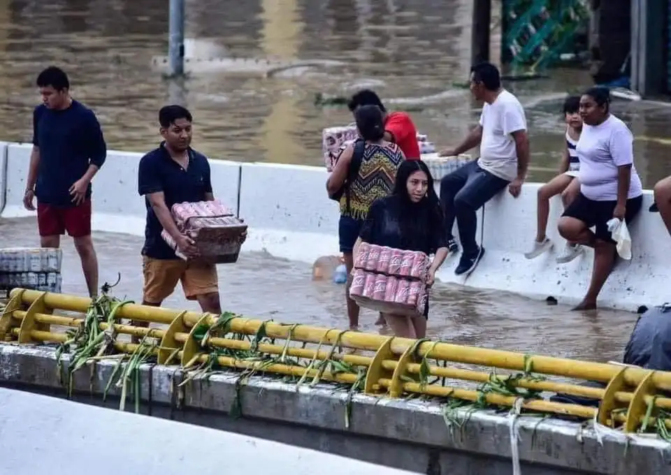 Personas cargando cervezas robadas en Acapulco, caos tras paso de John.